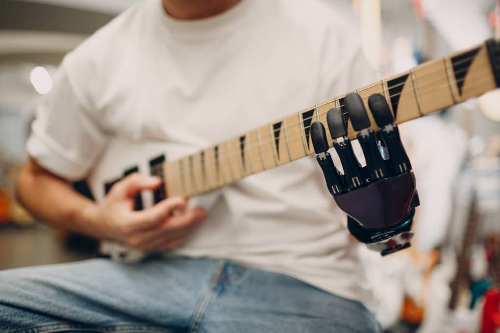 Ung kille spelar gitarr med hanprotes